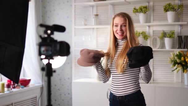 Μόδας blogger γυναίκα σε τζιν και ζιβάγκο δείχνει μοντέρνα καπέλα στην κάμερα. Στυλίστρια influencer κορίτσι δείχνει μοντέρνα καπέλα γυρίσματα επεισόδιο vlog για το κανάλι βίντεο της. Ο ηγέτης της γνωμοδότησης καθορίζει τις τάσεις. — Αρχείο Βίντεο