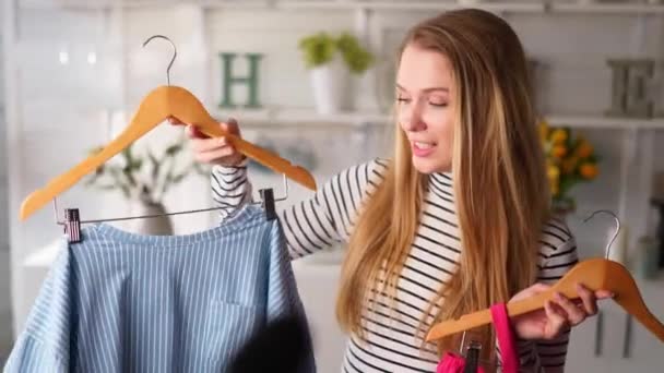 Blogueuse de mode femme en jeans et col roulé montrant des chemises colorées décontractées à la caméra. Styliste influenceuse fille montrant des vêtements à la mode filmant épisode vlog pour sa chaîne. Le leader d'opinion définit les tendances. — Video