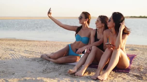 Amici multirazziali sorridenti seduti insieme su un asciugamano sulla spiaggia di sabbia bianca durante la loro vacanza in una destinazione idilliaca scena natura. Uomini e donne si rilassano sulla riva vicino al mare. — Video Stock