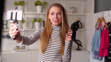 Boğazlı kazaklı moda blogcusu kadın akıllı telefon fotoğraf makinesinde yüksek topuklu ayakkabılar gösteriyor. Moda ayakkabılı stilist kız, kanal için video blogu çekiyor. Fikir lideri eğilimleri belirler.