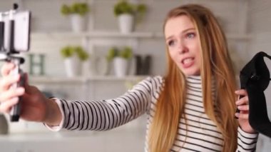 Boğazlı kazaklı moda blogcusu kadın akıllı telefon fotoğraf makinesinde yüksek topuklu ayakkabılar gösteriyor. Moda ayakkabılı stilist kız, kanal için video blogu çekiyor. Fikir lideri eğilimleri belirler.