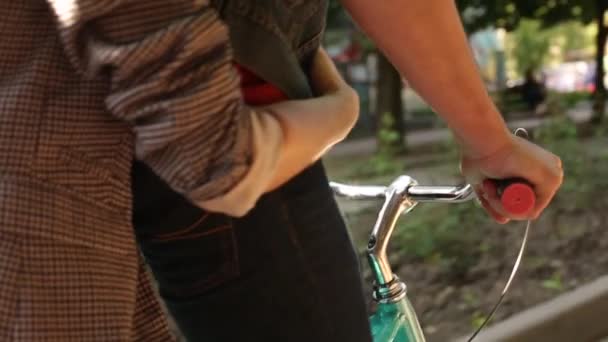 Visão traseira da mulher abraçando o homem se divertindo andando de bicicleta. Casal jovem andando de bicicleta juntos no parque. namorado romântico de bicicleta com namorada feliz no rack de carga na rua da cidade. Movimento lento . — Vídeo de Stock