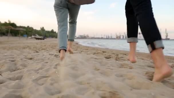 Terug lage hoek uitzicht van romantische paar voeten lopen op zand hand in hand op het strand in de buurt van de zee in slow motion. Vriendje en vriendinnetje hebben plezier aan de oceaan. Man en vrouw die samen verliefd zijn. — Stockvideo