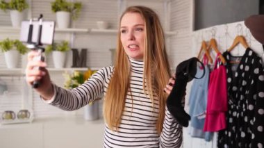 Boğazlı kazaklı moda blogcusu kadın akıllı telefon fotoğraf makinesinde yüksek topuklu ayakkabılar gösteriyor. Moda ayakkabılı stilist kız, kanal için video blogu çekiyor. Fikir lideri eğilimleri belirler.