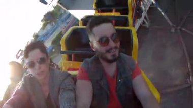 Hız trenine binen çiftin selfie videosu. Hippi adam ve şık kadın lunapark gezilerinde eğleniyorlar. Arkadaşlar aşırı binicilik, kahkaha ve heyecan çığlığı, adrenalin.