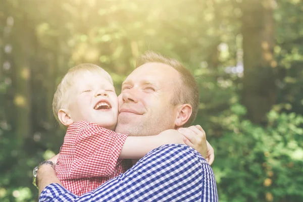 Father and son hugging and looking at the sun.