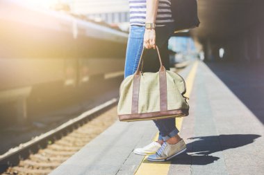 Bir tren istasyonunda bir çanta tutan kadın.