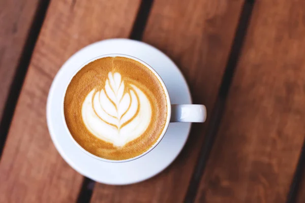 Uma xícara de café com arte latte na mesa de madeira . — Fotografia de Stock
