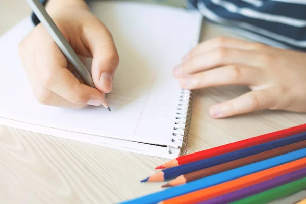 Niño sosteniendo lápiz y escritura . — Foto de Stock