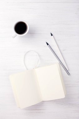 Bir fincan kahve ve masanın üstünde defter.