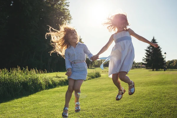 两个欢快的女孩跳着日落 夏季活动和休闲 — 图库照片