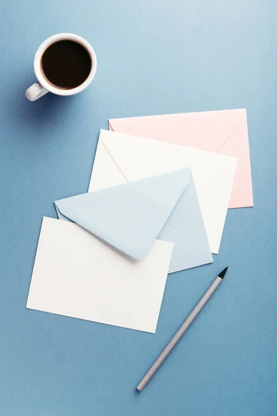 Kleurrijke enveloppen met koffie op grijze tafel. — Stockfoto