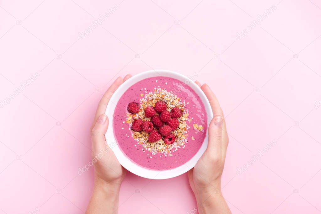 Hands holding smoothie bowl.