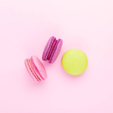 Üç renkli macarons pembe üzerinde.
