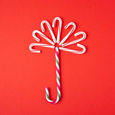 Şemsiye şeker kamışı lolipop kırmızı zemin üzerine yapılmış. Minimal tarz kartı.