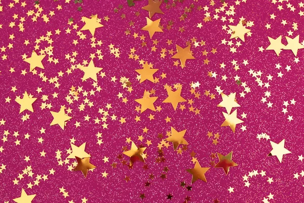 Конфетти Золотые звезды на розовом фоне . — стоковое фото