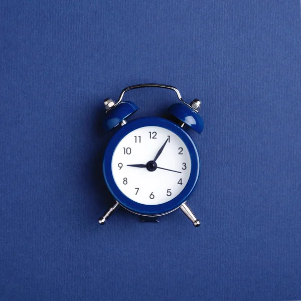 Reloj despertador sobre fondo azul oscuro . — Foto de Stock