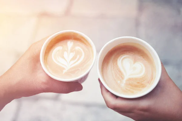 Take-away coffee s in hands with latte art.