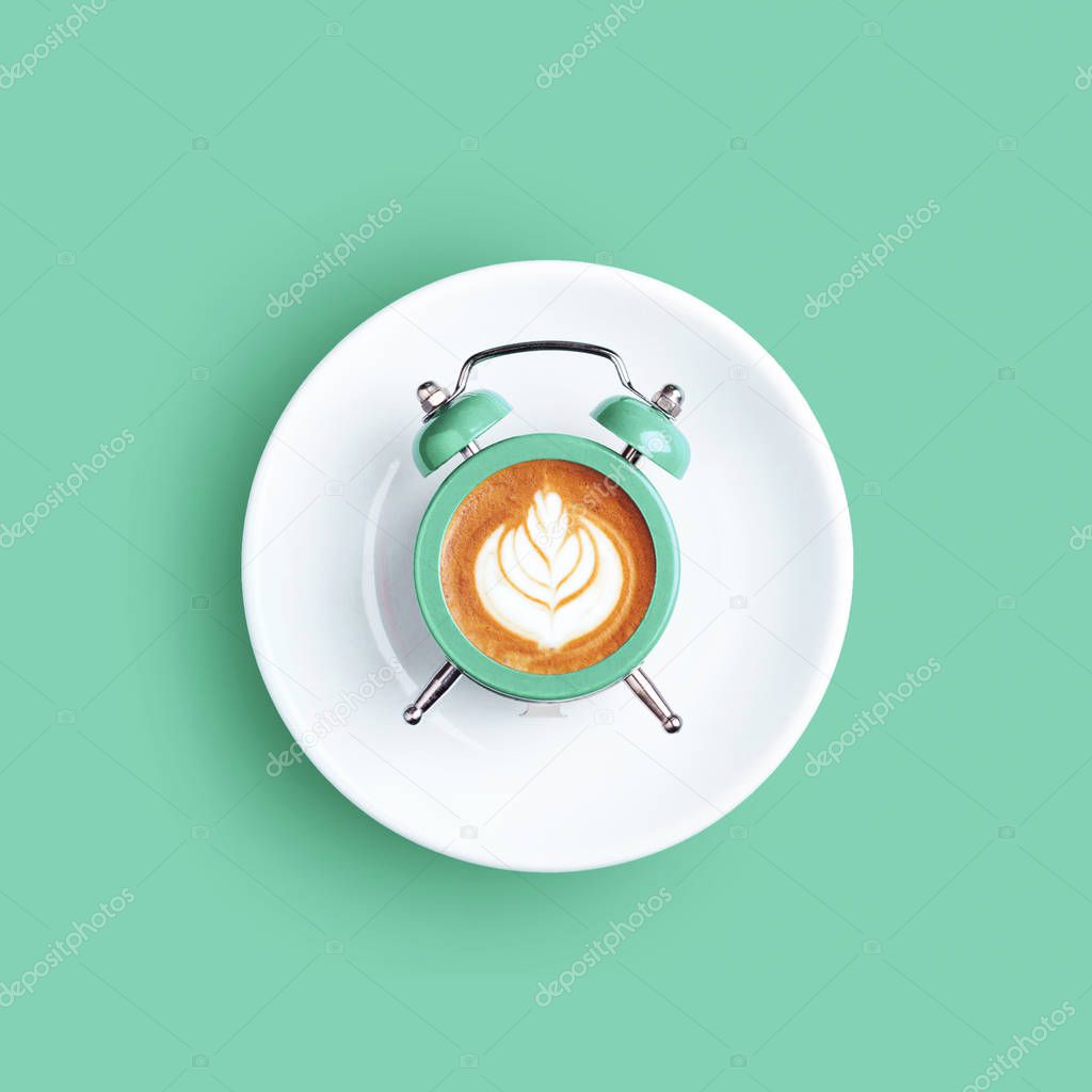 Clock with the dial of coffee on mint background.