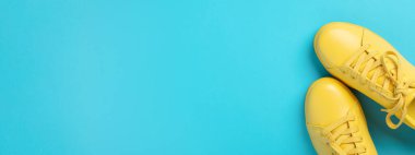 Mavi arkaplanda bir çift sarı ayakkabı..