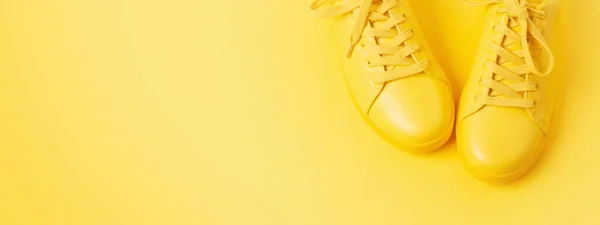 Pair of yellow shoes on yellow background.