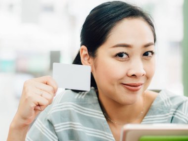 Mutlu Asyalı kadın tablete online alışveriş için beyaz mockup kredi kartı ile.