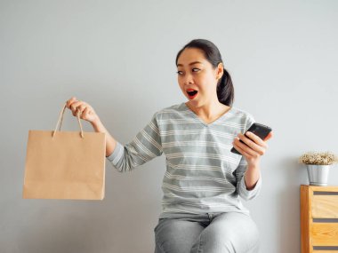Ürün boş kağıt torba gösteren Asyalı kadın o satın almak online. Online alışveriş kavramı.