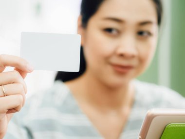 Mutlu Asyalı kadın tablete online alışveriş için beyaz mockup kredi kartı ile.