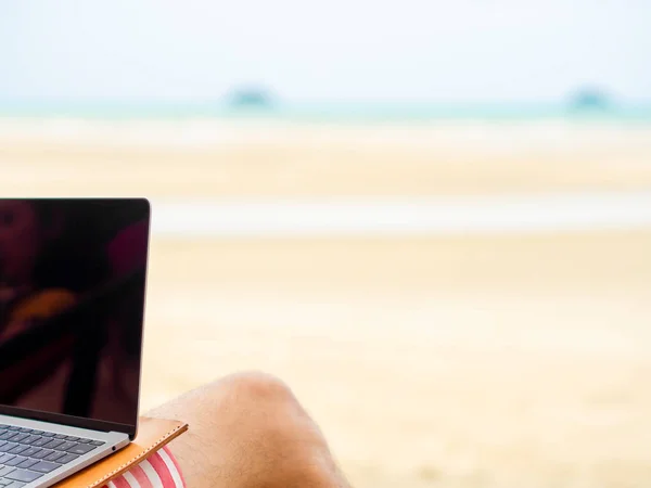 Man relax on camp bed and working online while on vacation at the beach in Thailand.