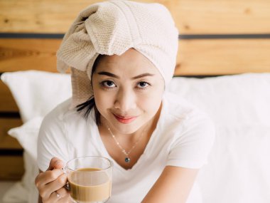 Asyalı kadın sabah kahve içmek kadar yakın ve yatağında duştan sonra rahatla.