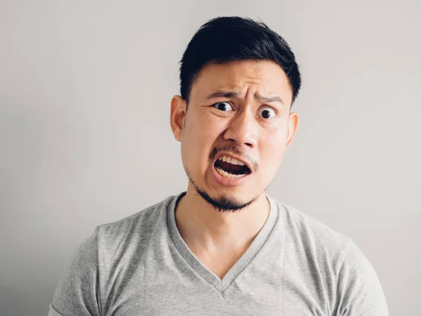 Headshot photo of Asian man with angry and furious face. on grey background.