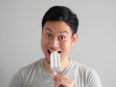 Asyalı adamın kafa vurdu buz pop komik surat ile yiyor.