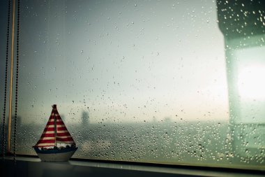 Biraz güneş ışığı ile yağmurlu windows kenarına küçük Yelkenli.
