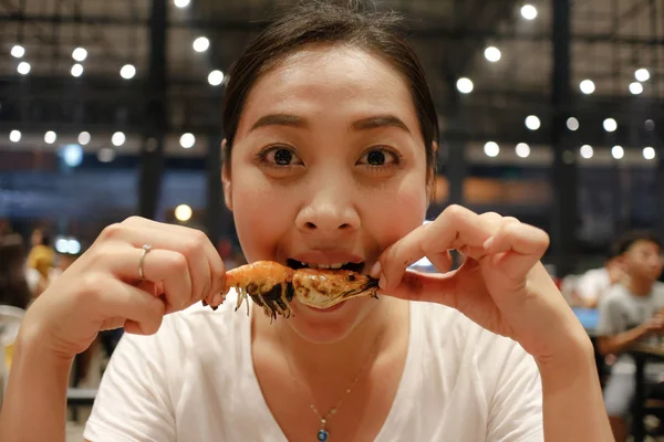 アジアの女性の幸せな食べるおいしい一口顔とエビのグリル — ストック写真