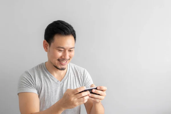 Smile and happy face of Asian man play mobile game.