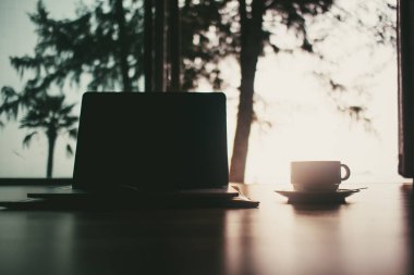 Laptop ve kahve fincan sıcak gün ışığına iş kavramı ile ahşap zemin üzerinde ve rahatla.