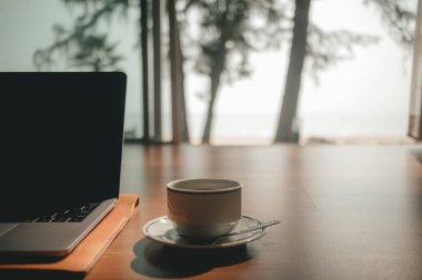 Laptop ve kahve fincan sıcak gün ışığına iş kavramı ile ahşap zemin üzerinde ve rahatla.