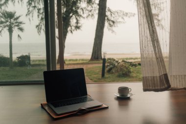 Concept of work and relax. Laptop and hot coffee cup at door step with autumn beach view. clipart