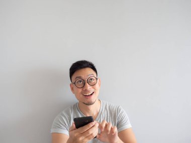 Asya adam ne smartphone izole gri arka plan üzerinde görmekten mutlu.