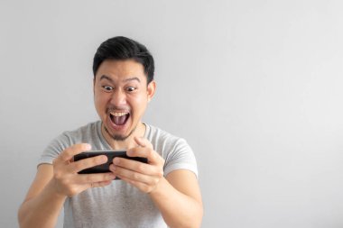 Asyalı adamın mobil oyun oynamak için bağımlısı deli ve komik yüzü.