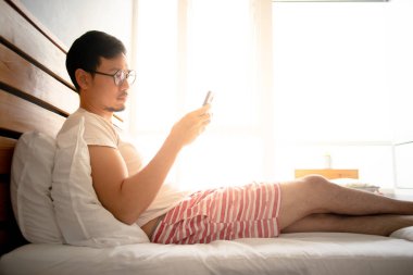 Asya adam onun smartphone kullanmak ve onun yatağında sabah sakin ol.