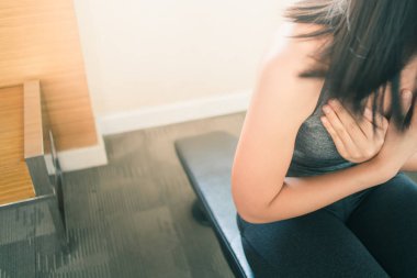 Asyalı kadın fitness salonunda bankta oturmak.