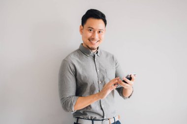 Yakışıklı Asyalı adamın gülen yüzü. Akıllı telefon kullan..