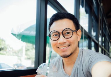 Selfy gözlüklü Asyalı adam kendini kafede kahve içmek.