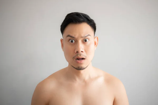 Shock and surprise face of man in topless portrait isolated on gray background.