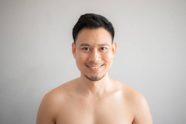 Üstsüz portre gri arka plan üzerinde izole erkekte gülümseme.