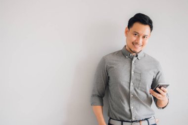Yakışıklı Asyalı adamın gülen yüzü. Akıllı telefon kullan..