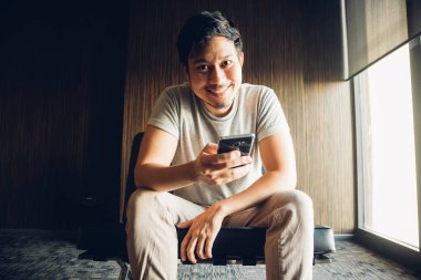 Asya adam kullanma smartphone Oda karanlık köşesinde.