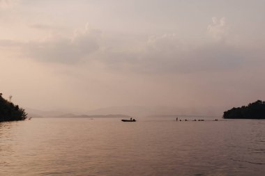 Büyük güzel gölün sıcak ve pürüzsüz günbatımı manzara görünümü.