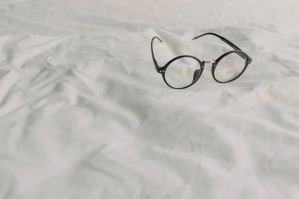 Beyaz Yatak Çarşafında Siyah Plastik Tapınak Ile Gözlük Okuma Dinlenmek — Stok fotoğraf
